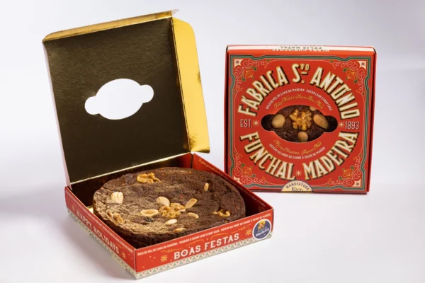 Bolo de Mel de Cana da Fábrica Santo António, edição de Natal, caixa vermelha aberta com o bolo visível, interior dourado e caixa fechada ao lado