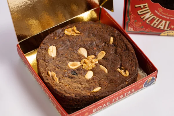 Bolo de Mel de Cana da Fábrica Santo António, edição de Natal, foto vista de cima, bolo com pedaços de noz, amêndoa, em caixa vermelha e dourada com "Boas Festas"